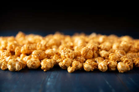 Heap of Caramel popcorn on blue rustic table and black background with copy spaceの写真素材