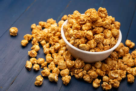 Caramel Popcorn in white bowl on rustic blue wooden table. Close up. Copy space for your textの写真素材