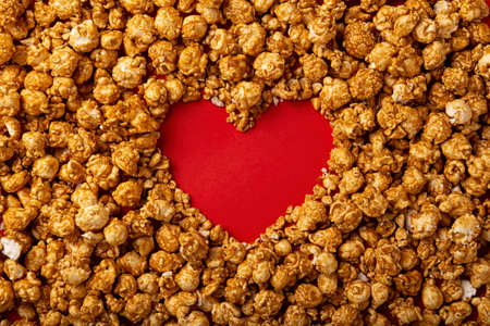 love concept image of heart shape frame made of caramel popcorn on red backgroundの写真素材