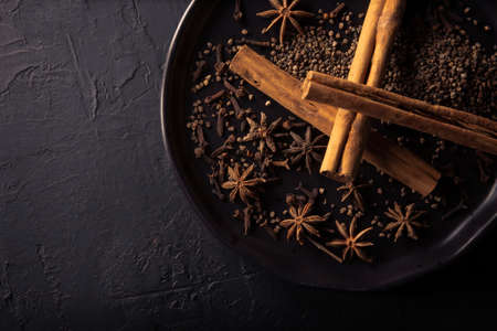 Selection of various spices on textured black background. cardamom, clove, cinnamon, star anise. Spices for hot spiced red wine. flat layの写真素材