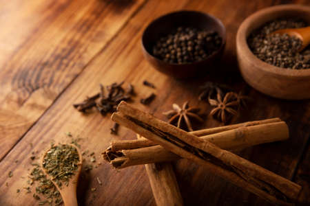 Cinnamon sticks and various spices on wooden rustic board background. Pepper, cardamom, clove, star anise, dehydrated parsley. close-upの写真素材