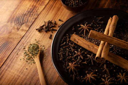 Various spices on wooden rustic board background. Pepper, cardamom, clove, cinnamon, star anise, dehydrated parsley. close-upの写真素材