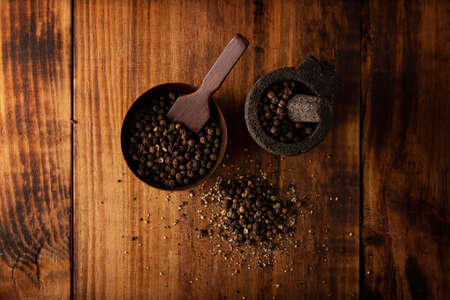 Black pepper in a small Molcajete (traditional Mexican version of the mortar and pestle) and small bowl on rustic wooden background. top viewの写真素材