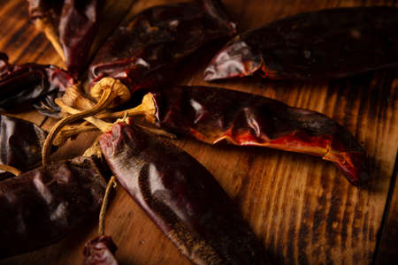 Guajillo chile. This Mexican chili is the dried form of mirasol chili and are used in a variety of Mexican preparations. Rustic wooden board. close-upの写真素材