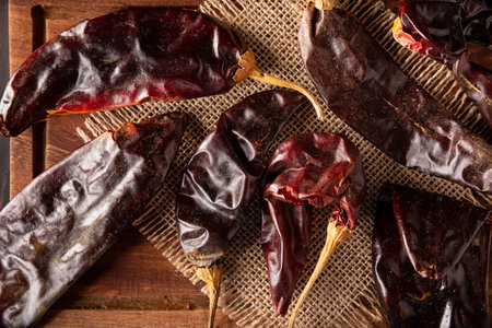 Guajillo chile. This Mexican chili is the dried form of mirasol chili and are used in a variety of Mexican preparations. Rustic wooden board.の写真素材