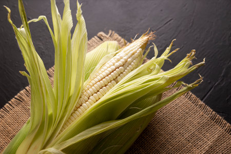 Top View Image of raw white corn on the cob on black rustic surface. copyspace. close up.の写真素材