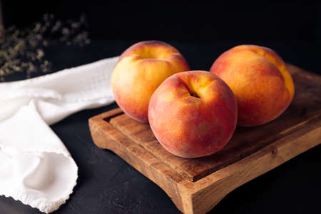 Whole ripe peaches (Prunus persica) on rustic cutting board. Close up pictureの写真素材