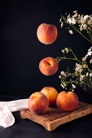 Whole ripe peaches (Prunus persica) floating on rustic cutting board. black backgroundの写真素材