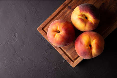 Whole ripe peaches (Prunus persica) on rustic cutting board. Top view with copy spaceの写真素材
