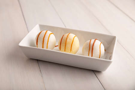 Ice cream Mochis with caramel (cajeta). Traditional Japanese dessert made from rice flour. Close up on white wooden surface.の写真素材