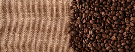 Roasted Coffee beans close up on burlap background. Panoramic image. Top view with copy space for your text.の写真素材