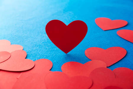 Paper cut red hearts shape on blue textured background with copy space. Concept image. Valentine's day, mother's day, birthday greeting cards, invitation, celebrationの写真素材
