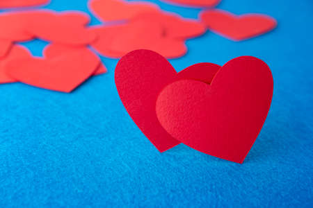 Paper cut red hearts shape on blue textured background with copy space. Concept image. Valentine's day, mother's day, birthday greeting cards, invitation, celebrationの写真素材