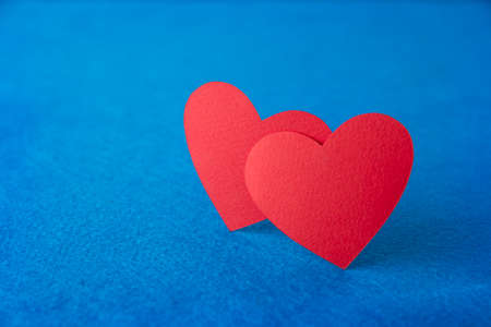 Paper cut red hearts shape on blue textured background with copy space. Concept image. Valentine's day, mother's day, birthday greeting cards, invitation, celebrationの写真素材