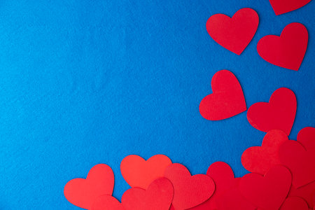 Paper cut red hearts shape on blue textured background with copy space. Concept image. Valentine's day, mother's day, birthday greeting cards, invitation, celebrationの写真素材