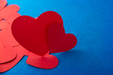 Paper cut red hearts shape on blue textured background with copy space. Concept image. Valentine's day, mother's day, birthday greeting cards, invitation, celebrationの写真素材