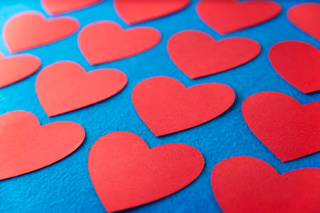 Paper cut red hearts shape on blue textured background with copy space. Concept image. Valentine's day, mother's day, birthday greeting cards, invitation, celebrationの写真素材