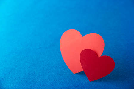 Paper cut red hearts shape on blue textured background with copy space. Concept image. Valentine's day, mother's day, birthday greeting cards, invitation, celebrationの写真素材