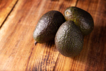 Mexican avocado (persea americana) on rustic wooden table. Main ingredient to prepare guacamole. Close up image with copy space.の写真素材