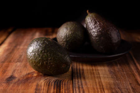 Whole Mexican avocado (persea americana) on rustic wooden table. Main ingredient to prepare...