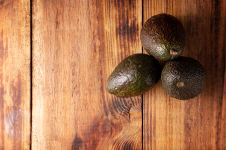 Mexican avocado (persea americana) on rustic wooden table. Main ingredient to prepare guacamole. Top view image with copy space.の写真素材