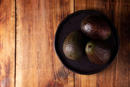 Mexican avocado (persea americana) on rustic wooden table. Main ingredient to prepare guacamole. Top view image with copy space.の写真素材