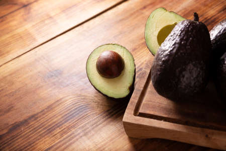Half Mexican avocado (persea americana) on rustic wooden table. Main ingredient to prepare guacamole. Close up pictureの写真素材