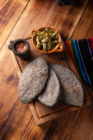 Tlacoyos. Mexican pre hispanic dish made of blue corn flour patty filled with fried beans. Popular street food in Mexico. Top view.の写真素材
