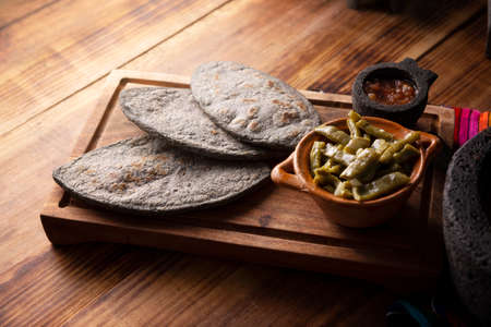 Tlacoyos and Nopales. Mexican pre hispanic dish made of blue corn flour patty filled with fried beans. Popular street food in Mexico.の写真素材