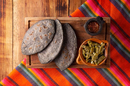 Tlacoyos and Nopales. Mexican pre hispanic dish made of blue corn flour patty filled with fried beans. Popular street food in Mexico. Top view image.の写真素材