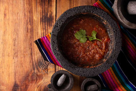 Molcajete with red sauce. Traditional mexican version of mortar and pestle handmade of volcanic stone. Essential element in the preparation of the authentic Mexican sauceの写真素材