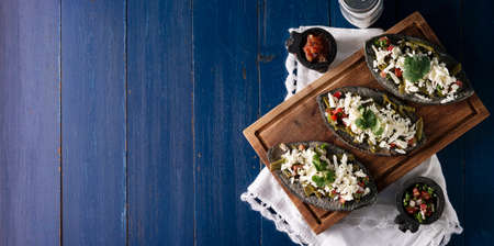 Mexican Tlacoyos. Mexican pre hispanic dish made of blue corn flour patty filled with fried beans. Popular street food in Mexico. Panoramic image with copy space. top viewの写真素材