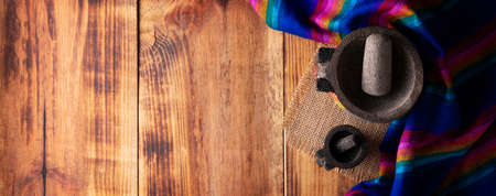 Mexican food cooking background with colorful traditional fabric and empty molcajetes on rustic wooden table. Panoramic top view with copy space.の写真素材