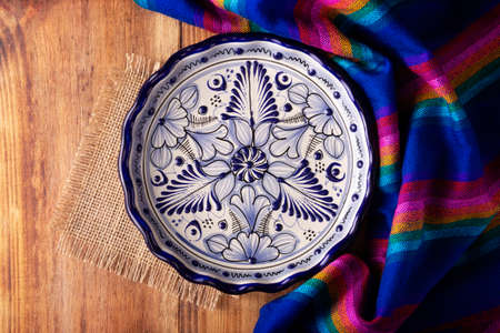 Mexican Cuisine Background, colorful traditional fabric and empty talavera style plate on wooden rustic table. flat layの写真素材