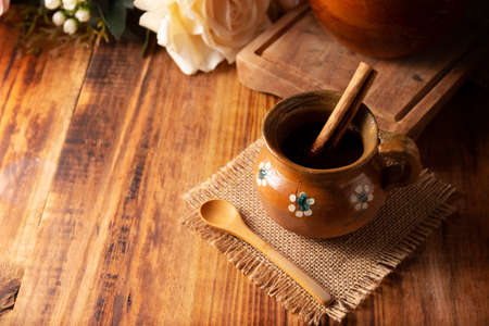 Authentic homemade mexican coffee (cafe de pot) served in traditional clay mug (Jarrito de barro) on rustic wooden table.の写真素材