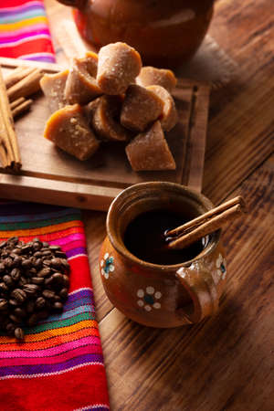 Coffee pot. Traditional Mexican coffee and basic ingredients for its preparation, coffee, cinnamon and piloncillo, served in a clay cup called "jarrito" on a rustic wooden surface.の写真素材