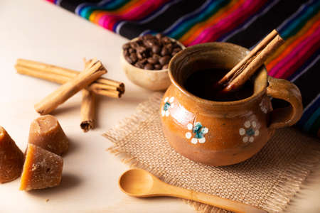 Coffee pot. Traditional Mexican coffee and basic ingredients for its preparation, coffee, cinnamon and piloncillo, served in a clay cup called "jarrito" on a rustic wooden surface.の写真素材