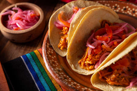 Cochinita Pibil Tacos. Typical Mexican stew from Yucatan, made from pork marinated with achiote and generally accompanied with beans and red onion with habanero chiliの写真素材