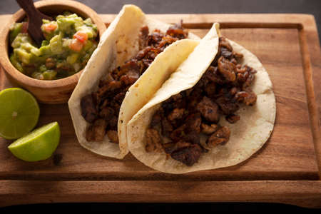 Steak tacos. Homemade grilled meat in a corn tortilla. Street food from Mexico, traditionally accompanied with cilantro, onion and spicy sauce or guacamoleの写真素材