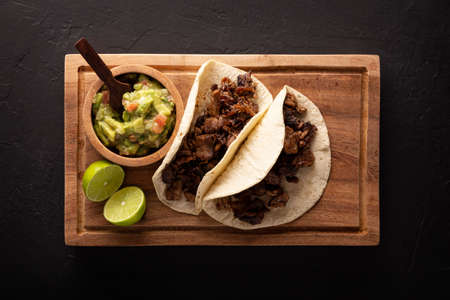 Steak tacos. Homemade grilled meat in a corn tortilla. Street food from Mexico, traditionally accompanied with cilantro, onion and spicy sauce or guacamoleの写真素材