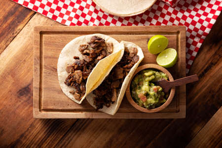 Steak tacos. Homemade grilled meat in a corn tortilla. Street food from Mexico, traditionally accompanied with cilantro, onion and spicy sauce or guacamoleの写真素材