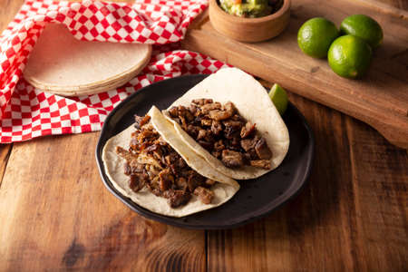 Steak tacos. Homemade grilled meat in a corn tortilla. Street food from Mexico, traditionally accompanied with cilantro, onion and spicy sauce or guacamoleの写真素材