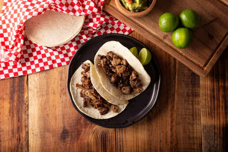 Steak tacos. Homemade grilled meat in a corn tortilla. Street food from Mexico, traditionally accompanied with cilantro, onion and spicy sauce or guacamoleの写真素材