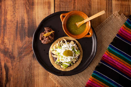 Chicken soup. Traditional homemade Mexican appetizer prepared with fried corn dough covered with chilled beans, green or red sauce, lettuce, cheese, onion and shredded chickenの写真素材