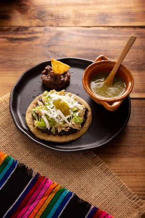 Chicken soup. Traditional homemade Mexican appetizer prepared with fried corn dough covered with chilled beans, green or red sauce, lettuce, cheese, onion and shredded chickenの写真素材