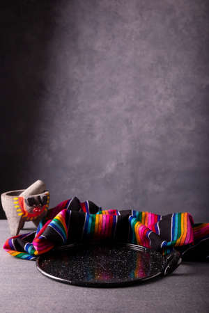 Mexican kitchen utensils, colorful traditional fabric, comal de peltre and molcajete on rustic gray surface. Copy space for your text.の写真素材