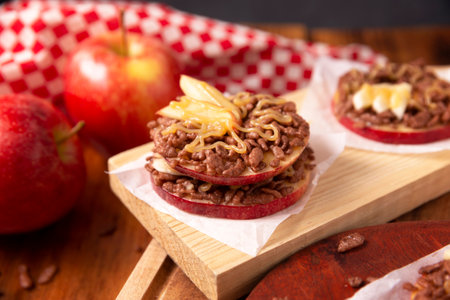 Creative party snack for holidays. Apple rounds with peanut butter, caramel and chocolate flavor puffed rice topping with banana slices. Funny appetizer for kids and adults.の写真素材