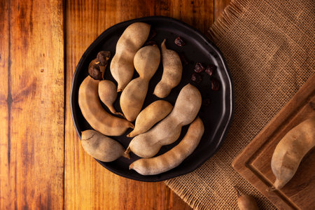 Tamarind fruit (Tamarindus indica) on wooden rustic table. Tropical fruit highly appreciated in several countries of the world. Closeup image.の写真素材