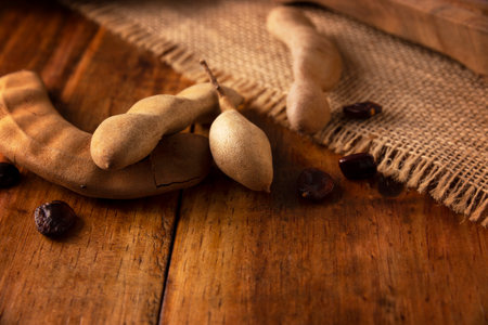 Tamarind fruit (Tamarindus indica) on wooden rustic table. Tropical fruit highly appreciated in several countries of the world. Closeup image.の写真素材