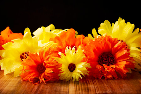 Colorful paper flowers on wooden table and black background. Decoration floral pattern, springtime, Easter, Birthday, Happy Womens Day, Mothers Day. Copy space for your message.の写真素材